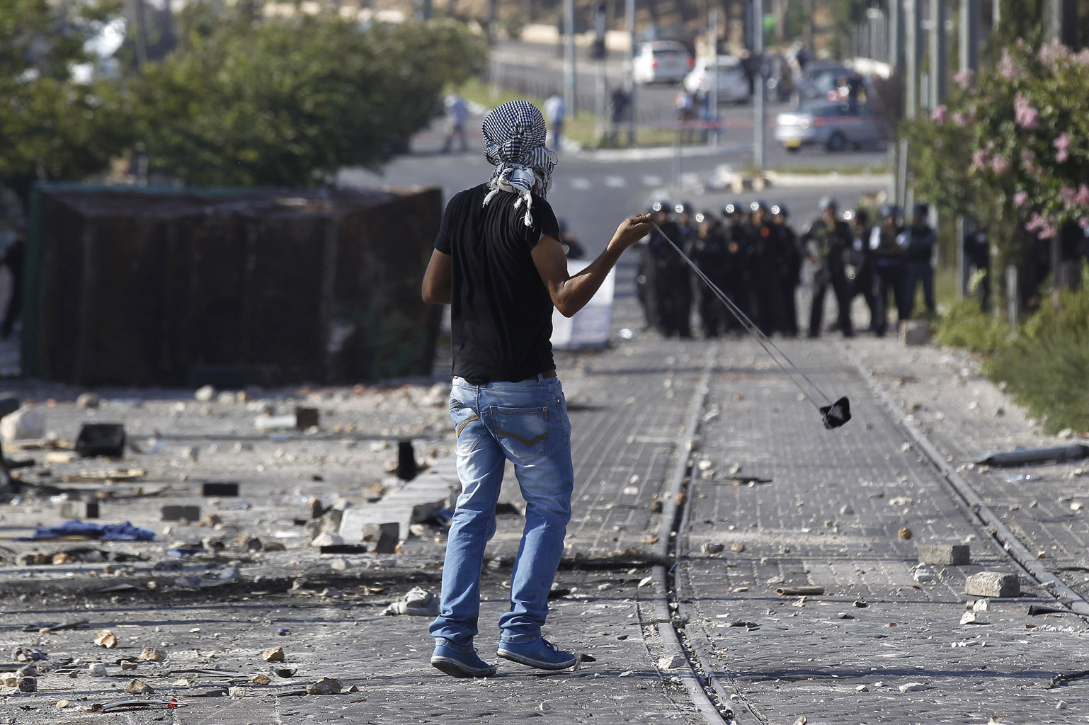 Palestyńczyk rzuca kamieniem w kierunku policji podczas zamieszek w Szuafat na przedmieściach Jerozolimy w dniu pogrzebu zamordowanego 16-latka. Fot. Ammar Awad/Reuters/Forum